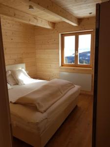a bed in a wooden room with a window at Almchalet Klippitzzauber in Bad Sankt Leonhard im Lavanttal