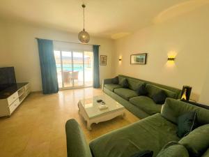 ein Wohnzimmer mit einem grünen Sofa und einem Tisch in der Unterkunft Luxury 4 bedroom villa with a heated pool in Hurghada