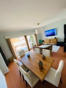a dining room with a wooden table and white chairs at Cabedelo Beach Loft in Darque