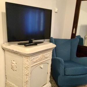 una TV sopra un comò con una sedia blu di L'angolo di Zia Anna a Montefalco
