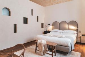 a white bedroom with a large bed and a table at Palazzo Fontana B&B e SPA in Gravina in Puglia