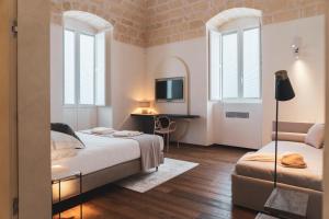 a bedroom with two beds and a desk and windows at Palazzo Fontana B&B e SPA in Gravina in Puglia