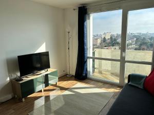 a living room with a tv and a large window at Roosevelt Cosy 2BR Easy Access to Paris Free parking in Saint-Germain-en-Laye