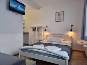 1 dormitorio con 1 cama y TV en la pared en Dom Wczasowy Sloneczko, en Mielno