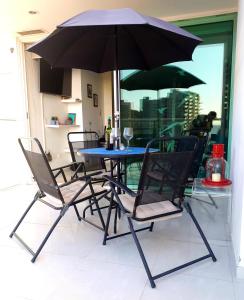 una mesa y sillas con una sombrilla en el patio en Apartamento Frente al Mar, en Santa Marta