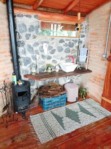 a room with a stove and a stone wall at Tiny Houses O Olival - aluguel temporada in Cunha