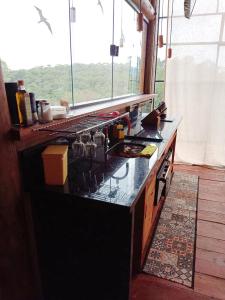 a kitchen with a black counter top with a window at Tiny Houses O Olival - aluguel temporada in Cunha