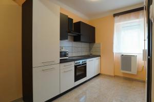 a kitchen with white cabinets and black appliances at Lia Apartman Pécs in Pécs