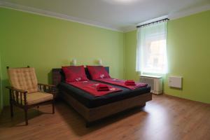 a bedroom with a bed and a chair and a window at Lia Apartman Pécs in Pécs