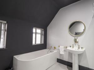 een badkamer met een bad, een wastafel en een spiegel bij 1 Seafield Street in Cullen