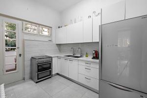 La cuisine est équipée de placards blancs et d'un réfrigérateur en acier inoxydable. dans l'établissement Rechavia Apartment, à Jérusalem