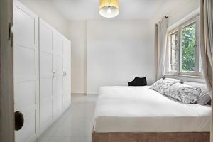 - une chambre blanche avec un lit et une fenêtre dans l'établissement Rechavia Apartment, à Jérusalem