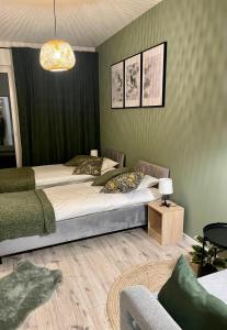 a bedroom with two beds and a couch at Apartments Sleep & GO Modlin Airport in Nowy Dwór Mazowiecki