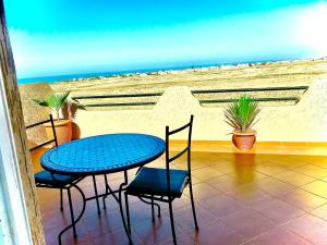 una mesa y sillas en un balcón con vistas a la playa en Tawada, en Mirleft