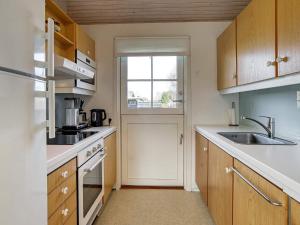eine kleine Küche mit einem Waschbecken und einem Fenster in der Unterkunft 4 person holiday home in Dannemare in Dannemare