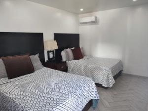 two beds in a room with white walls at Hotel Don Quijote in Mexicali