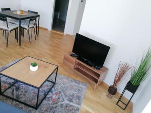 a living room with a flat screen tv and a table at Apartman Kedar in Arandelovac