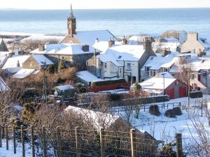 una pequeña ciudad cubierta de nieve con una torre de reloj en Fiddlers Rest en Ballantrae