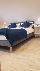 un grande letto con lenzuola blu e cuscini blu di Pueblo Apartamenty a Stegna