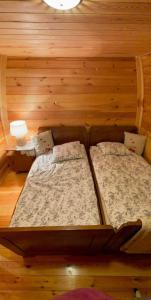 two beds in a room with wooden walls at Poleskie zacisze, domek Bocian, kominek, balia,sauna,wifi in Helenin