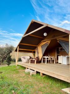 a tent with a wooden deck in a field at Glamping Grancia in Grosseto