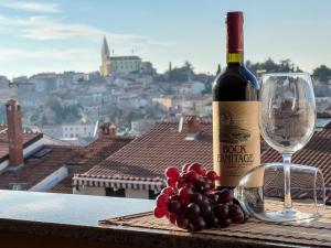 a bottle of wine and a glass and grapes on a table at Apartments Jurić in Vrsar