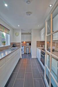 a large kitchen with white cabinets and a tile floor at Three bedroom house in Culloden, Inverness in Culloden