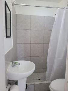 a white bathroom with a sink and a toilet at Fundo Chakas in San Antonio