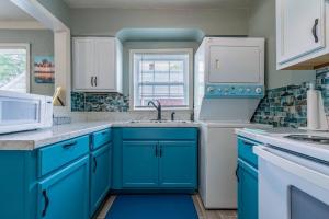a blue kitchen with white cabinets and a sink at MIKA SPRINGS Beach Inspired Home! in Memphis