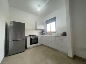 una cucina con armadi bianchi e frigorifero in acciaio inossidabile di Garden North With built in BBQ a Kiryat Shmona