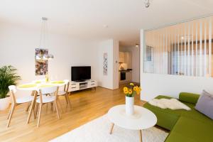 a living room with a green couch and a table at Rafael Kaiser - Aurea Apartment - Contactless 24h Check-In - in Vienna