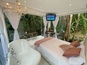 - une chambre avec une baignoire, un lit et une télévision dans l'établissement Loft Vidro Vitoriano em Condomínio Rota do Vinho São Roque, à Mairinque