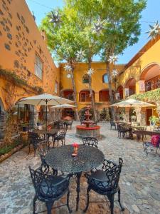 an outdoor patio with tables and chairs and umbrellas at Hotel Hacienda Monteverde San Miguel de Allende in San Miguel de Allende