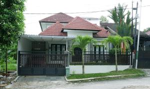 a white house with a black fence and palm trees at Blue Villa in Balikpapan