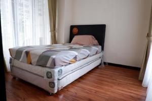 a bed in a room with a wooden floor at Blue Villa in Balikpapan