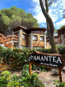 a sign in front of a building with a tree at Departamentos Amantea in Mar de las Pampas