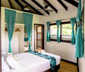 1 dormitorio con 1 cama grande y cortinas azules en Vakanananu Retreat en Matei