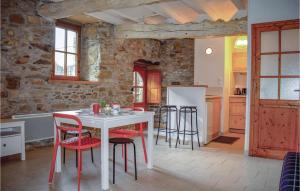 cocina con mesa blanca y sillas rojas en Amazing Home In Quemper Guzennec With Kitchen, en Quemper-Guézennec