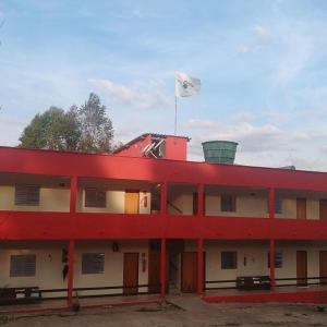 a red building with a flag on top of it at Pousada dos Tucanos in São Thomé das Letras