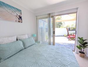 een slaapkamer met een bed en een glazen schuifdeur bij Grand Riviera Forster- waterfront, pool, wharf in Forster