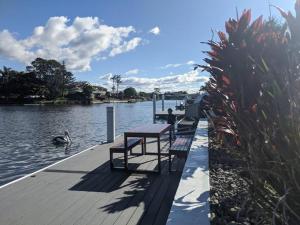 a row of benches sitting on a dock next to the water at Grand Riviera Forster- waterfront, pool, wharf in Forster