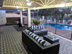 een patio met banken, een tafel en een zwembad bij Grand Riviera Forster- waterfront, pool, wharf in Forster