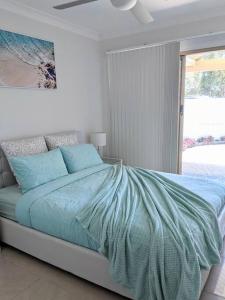 een slaapkamer met een bed met blauwe lakens en een raam bij Grand Riviera Forster- waterfront, pool, wharf in Forster