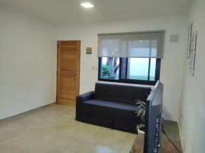 sala de estar con sofá negro y ventana en Complejo Claret Departamento B, Zona Norte en Córdoba