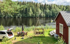 a car parked next to a house with a picnic table next to a river at Lovely Home In Rda With House Sea View in Råda