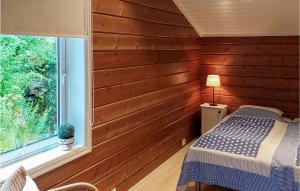 a bedroom with wooden walls and a bed and a window at Cozy Home In Rysstad With House Sea View in Rysstad