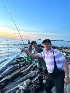 two men standing on the beach holding a fishing rod at ¡VILLA AZUL! LUGAR ENCANTADOR A 60 METROS DEL MAR :o ;) in Necoclí