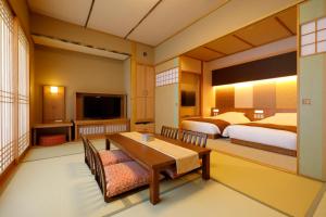 um quarto de hotel com duas camas e uma mesa e um quarto em Onyado Shikishima-kan em Kotohira