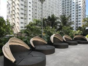 een rij tafels en stoelen met gebouwen op de achtergrond bij Shore Residences in Manilla