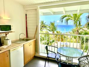 a kitchen with a table and a view of the ocean at Cannelle in Deshaies